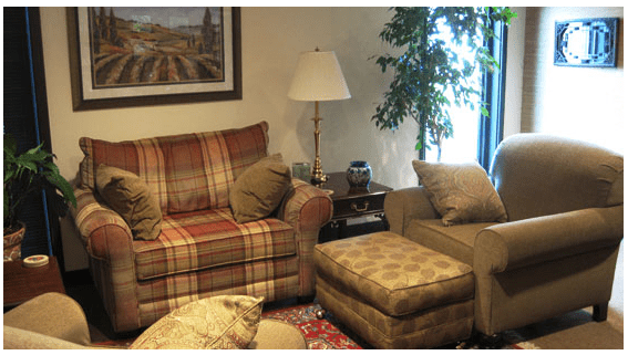 A Cozy Living Room Featuring a Couch, Chair, Ottoman, and a Lamp, Creating a Warm and Inviting Atmosphere.