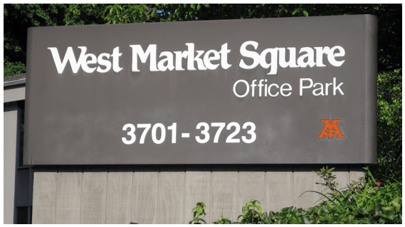Sign for West Market Square Office Park, Featuring the Name Prominently Displayed Against a Clear Blue Sky.